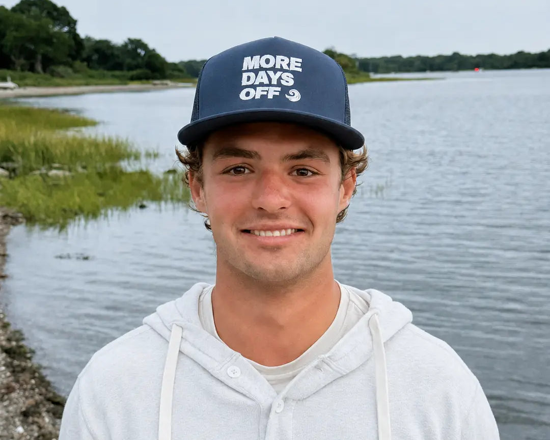 Model wearing the navy More Days Off hat by the water