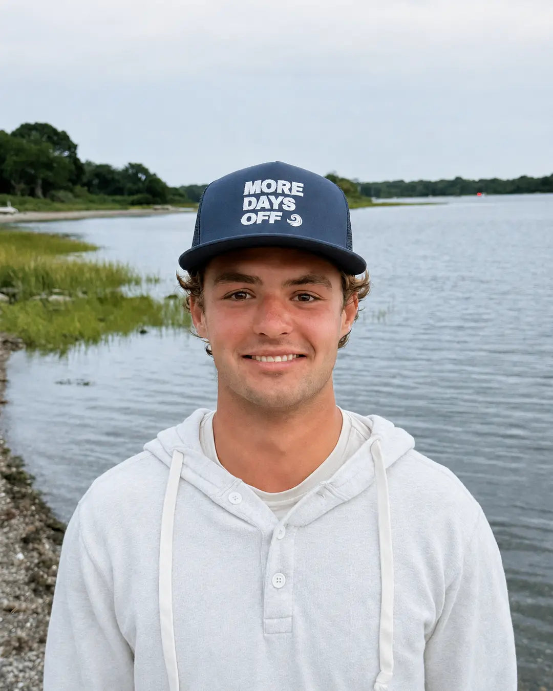 Model wearing the navy More Days Off hat by the water