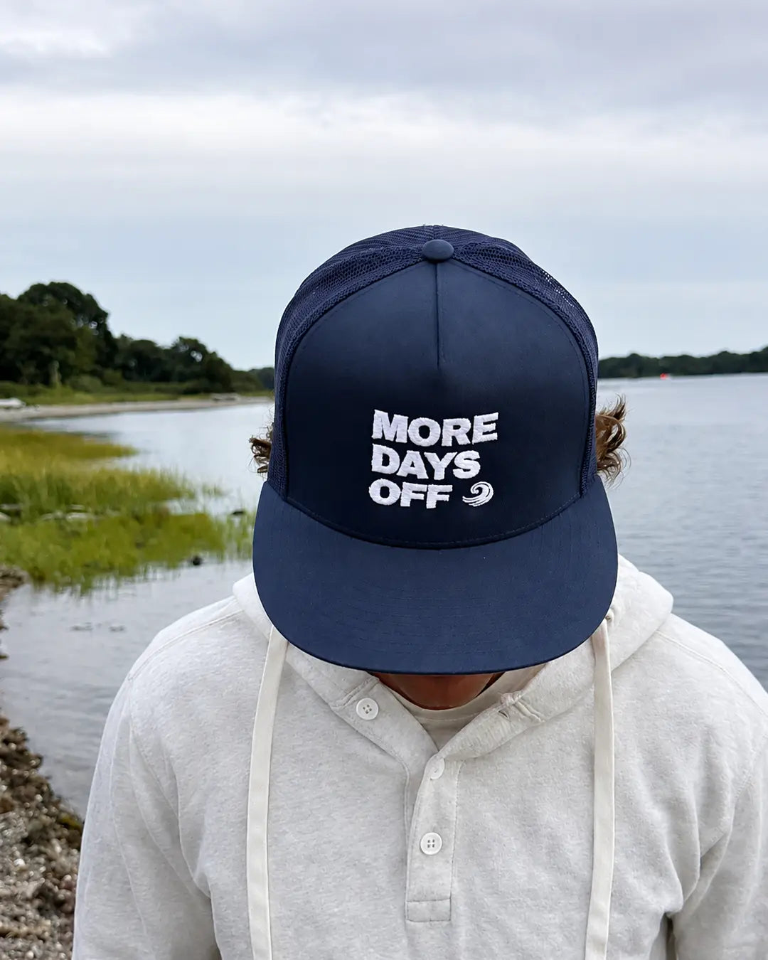 Close-up of white More Days Off embroidery on a navy hat