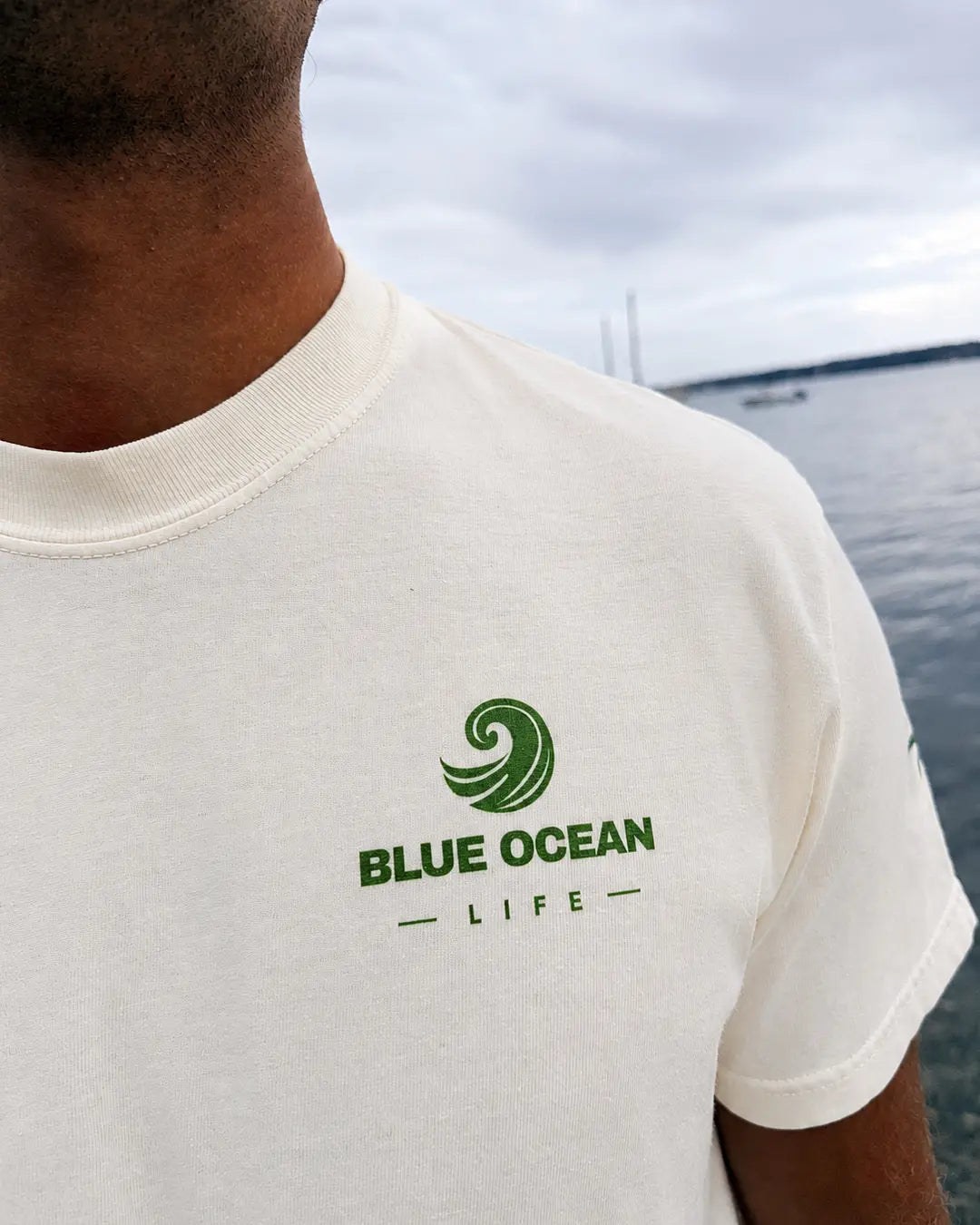 Close-up of the green Blue Ocean Life chest logo on the ivory tee