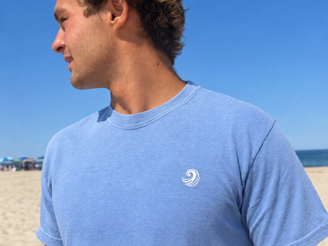 Close-up of the white Healing Wave embroidery on the denim blue tee