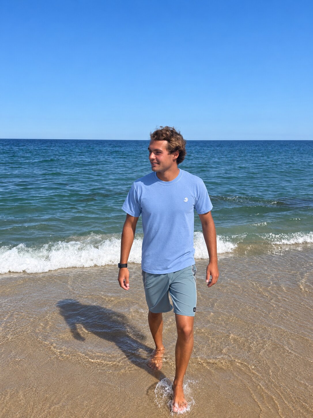Model walking in the ocean wearing the Healing Wave embroidered denim tee