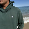Healing Wave embroidery detail on forest green hoodie
